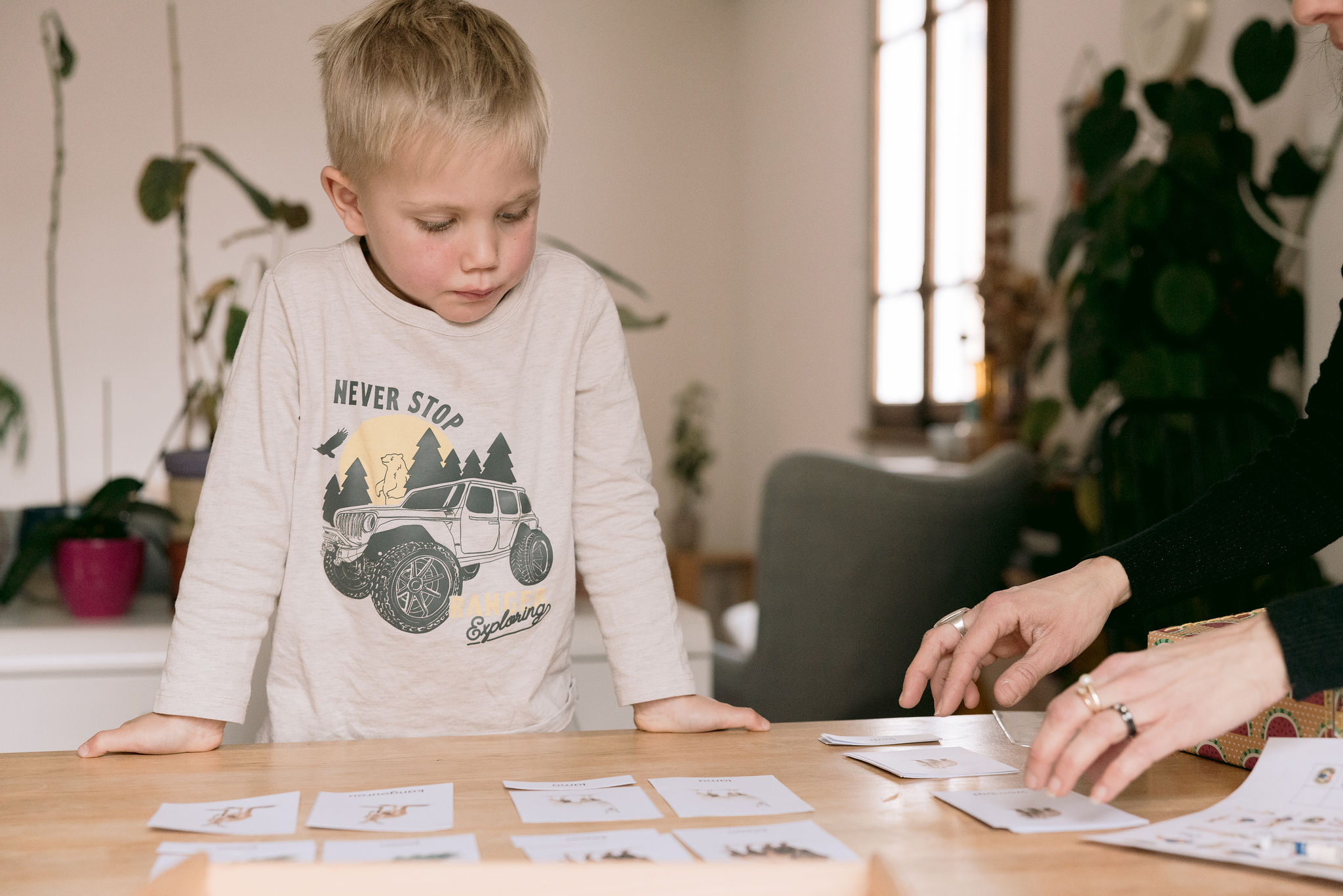 Enfant qui aligne des cartes illustrées sur une table, activité Montessori à imprimer